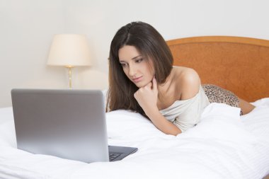 Yatakta dizüstü bilgisayarlı genç bir kadın