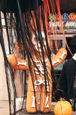 Kyiv, Ukrayna - 20 Ekim 2020. Korkunç Cadılar Bayramı süslemeleri. İskelet kostümlü zencefilli adam, pazarda çizilmiş kemikler ve balkabaklarıyla. Çocuklar şaka mı şeker mi?.