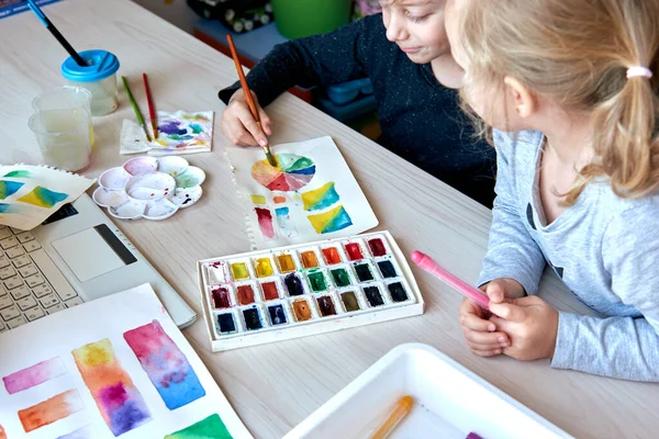 Παιδιά ζωγραφίζοντας εικόνες με ακουαρέλες κατά τη διάρκεια του μαθήματος τέχνης. Οι κόρες επικεντρώνονται στη ζωγραφική με πινέλο. Αδιάβροχη ρόδα και παλέτα. Θεωρία χρωμάτων αρχάρια μαθήματα χόμπι — Φωτογραφία Αρχείου