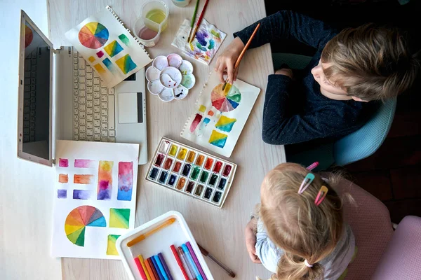 Gyerekek képeket festenek akvarell festékkel a művészeti óra alatt. A pupillák ecsettel rajzolnak. Akvarell színű kerék és paletta. Színelmélet kezdő hobbiórák — Stock Fotó