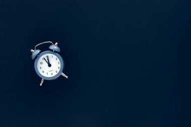 Mavi antika alarm saat 12 yönünde koyu arkaplanda izole bir saat gösteriyor. Uyan ve acele et. Sıcak satış, son fiyat, son şans. Yeni yıl geceyarısına geri sayım başladı. Metnin için boşluk kopyala.