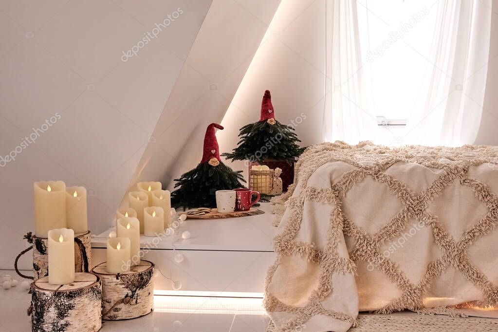 Beautiful holdiay DIY handmade home decoration. Cosy room decorated with candles and Christmas tree with presents under it. Hot drink on the table. New Year's interior in a photo studio.