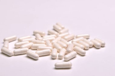 Renkli arka planda bir sürü beyaz kapsül hapı var. Sağlığınız için yararlı olan takviye ve ilaçlar.