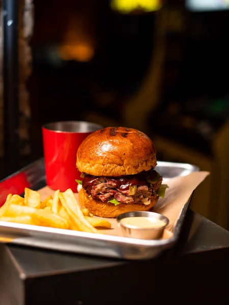 Tasty grilled burger with beef,cheese,bacon and sauce on wooden table with french fries and beer