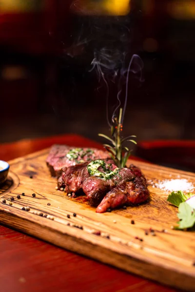 Entrecote Beef Grilled steak meat on wooden cutting boardon with rosemary branch, pepper and salt .