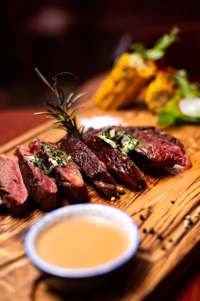 Entrecote Beef Grilled steak meat on wooden cutting boardon with rosemary branch, pepper and salt .