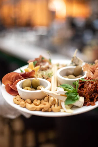 Assorted beer snacks, fast food. Blue cheese appetizer, cured meats, pickles, french fries, nachos, pistachios, chips and sauses with mug of beer.