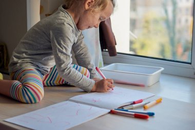 3 yaşındaki bir kız resim çizer. Çocuk evde, anaokulu ve anaokulu Covid-19 sırasında kapalı.