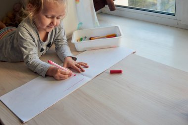 3 yaşındaki bir kız resim çizer. Çocuk evde, anaokulu ve anaokulu Covid-19 sırasında kapalı.