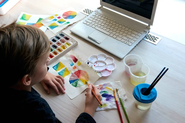 Chico pintura cuadros con acuarela pinturas durante la lección de arte en línea —  Fotos de Stock