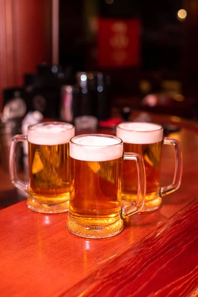 Pouring beer standing at the bar counter. Large craft wise beer in tap in cafe or pub menu. Toasting with friends at the bar