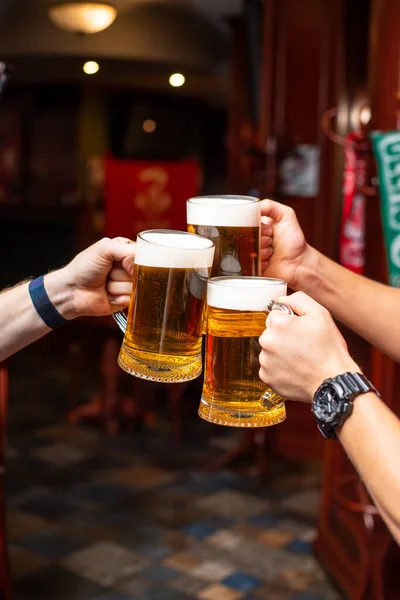 Pouring beer standing at the bar counter. Large craft wise beer in tap in cafe or pub menu. Toasting with friends at the bar