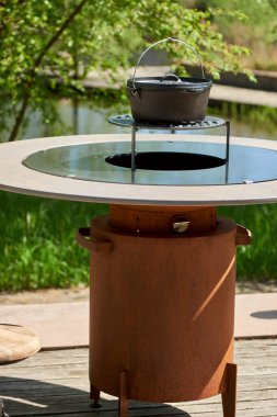 Tencere dibin kara seninki benden kara, seninki benden kara. Yuvarlak masa pişirme yüzeyi. Arka bahçede paslanmaz çelik ızgaralı barbekü ızgarası hazır ızgara yemeği. İçinde alevler olan ızgara..