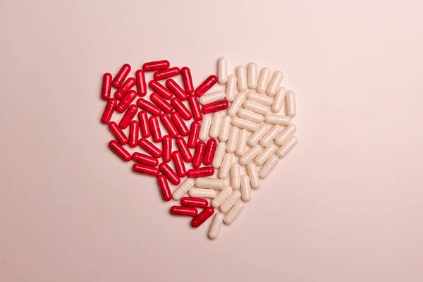 Hjärta gjord av vita kapsel piller vitamin på en färgstark bakgrund. Hälsotillskott och läkemedel — Stockfoto