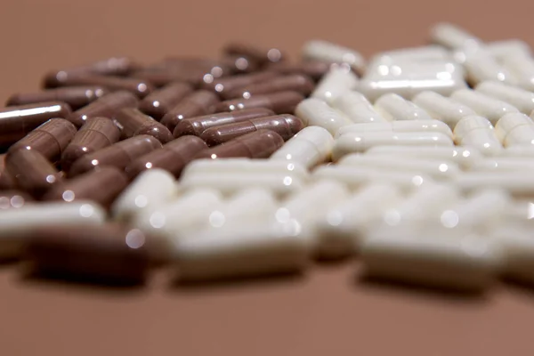 Muitas pílulas de cápsula branca e marrom em um fundo colorido. Suplementos de saúde e medicamentos — Fotografia de Stock