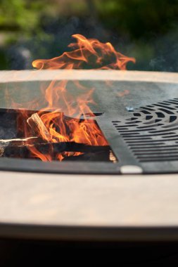 Tencere dibin kara seninki benden kara, seninki benden kara. Yuvarlak masa pişirme yüzeyi. Arka bahçede paslanmaz çelik ızgaralı barbekü ızgarası hazır ızgara yemeği. İçinde alevler olan ızgara..