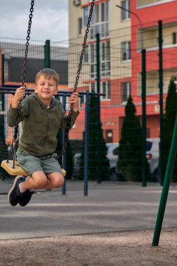 Çocuklar parkta oynarlar. Mutlu gülen çocuk, sallan ve dışarı tırman.