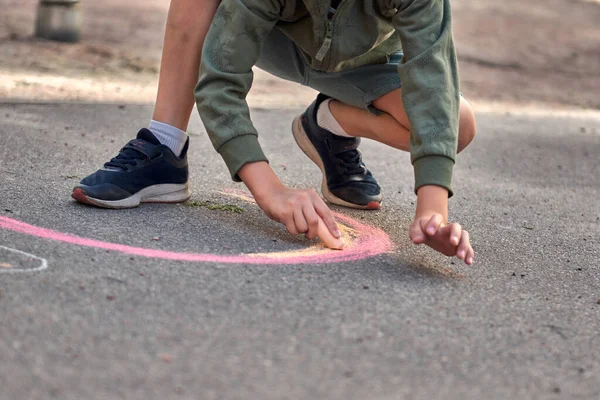 Los niños pintan afuera. Niño dibujando una tiza de color arco iris en el asfalto el patio de recreo — Foto de Stock