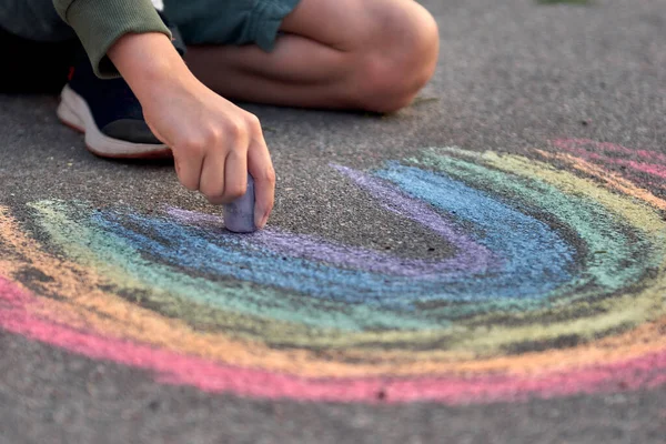 A gyerekek a szabadban festenek. Fiú rajz szivárvány színű kréta az aszfalton a játszótér — Stock Fotó