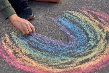 Çocuklar açık havada resim yapar. Güneşli yaz gününde asfalta gökkuşağı renkli tebeşir çizen bir çocuk portresi. Çocuklar oyun alanında oynarlar. Açık hava aktivitesi