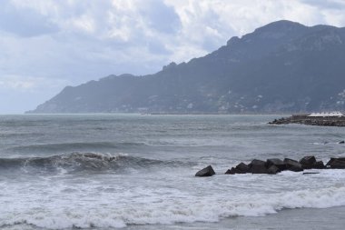 Deniz manzarası bulutlu ve dalgalı gökyüzü ile özel bir atmosfer yaratıyor.