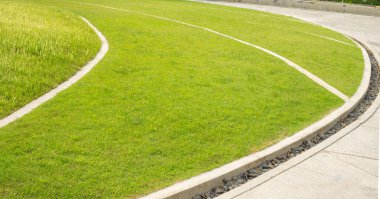 Pürüzsüz yeşil çimenler bahçe bahçesinde bir halı gibi, bakımlı manzaralar beyaz renkli beton kaldırımlarla süslenmiş.