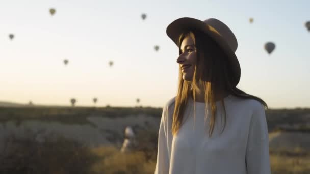 Woman watching the sunrise and hot air balloons. — Vídeo de stock