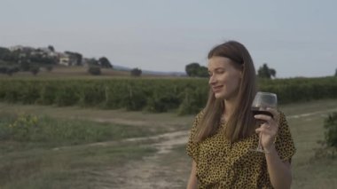 Üzüm bağında kırmızı şarap tatan güzel kız..