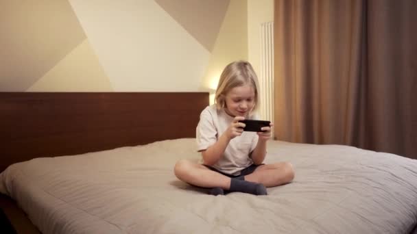 금발의 소년. 휴대 전화로 게임을 하는 어린이 — 비디오