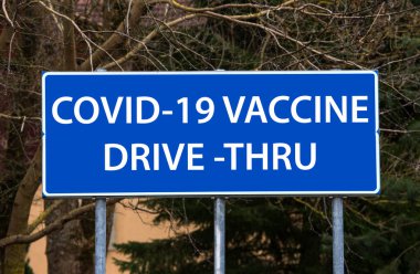 Covid-19 aşı sürücüsü konsepti. Mavi yol tabelası, aşının yapıldığı yeri gösteriyor. Fotoğraf değiştirmesi.