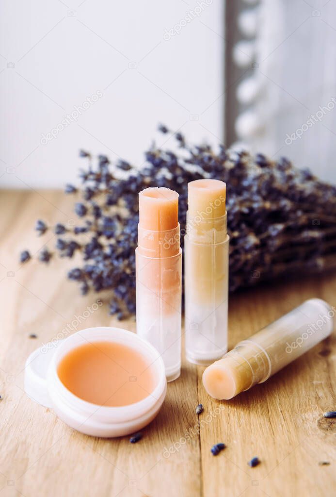 Make homemade natural organic ingredients lip balm. Handmade lip balm and lipstick inside container on natural wooden background and lavender for decoration.