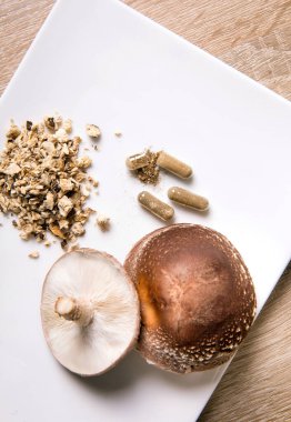 Shiitake Lentinus edoides mantar takviyesi kapsülleri taze Shiitake mantarları ve beyaz arka planda pudralanmış. Düz görünüm.
