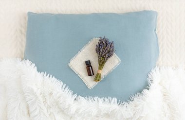 İyi geceler uykusu için lavanta çiçeği yağı kullanıyorum. Aromaterapi konsepti. Lavanta yağı ve bir buket kurutulmuş lavanta çiçeği ev odasındaki yumuşak yastıkta..