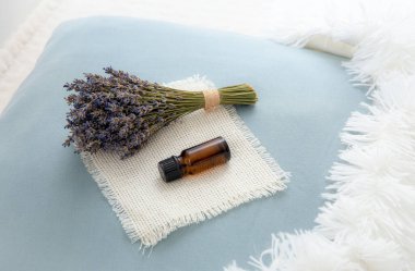 İyi geceler uykusu için lavanta çiçeği yağı kullanıyorum. Aromaterapi konsepti. Lavanta yağı ve bir buket kurutulmuş lavanta çiçeği ev odasındaki yumuşak yastıkta..