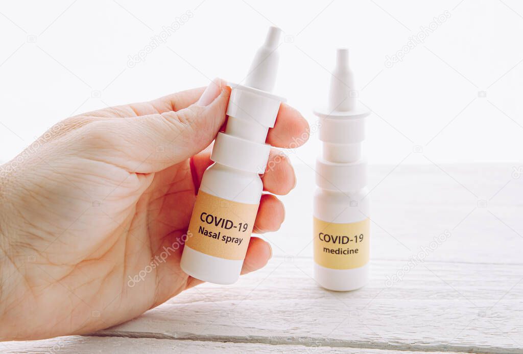 Person holding new treatment against Coronavirus COVID-19 nasal spray. Conceptual image of person hand holding new innovative nasal spray bottle with text COVID-19 SARS-CoV nasal spray.