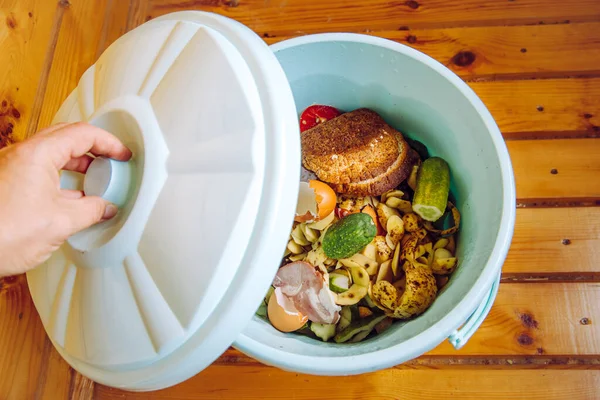 Organic food waste in garbage bin bucket with lid in home on floor to be composted.