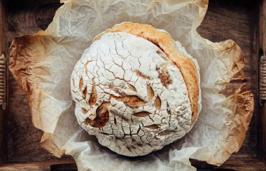 Ev yapımı ekşi ekmeği ahşap tepside, ev yapımı ekmeğin üzerinde düz bir şekilde duruyordu. Klasik stil.