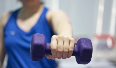 Kadın spor saat takıyor. Halteri kaldırıyor. Göğüs kasları için dudak kaldırıyor.
