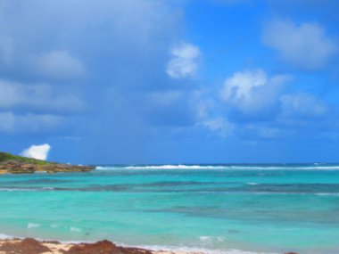 Bulutlu gökyüzünün altındaki bir körfezdeki turkuaz deniz.