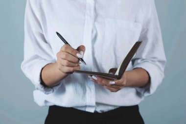 Gri arka planda kadın el kalemi ve not defteri