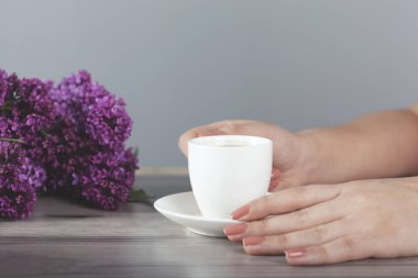 Kadın masada kahve ve leylak içiyor.