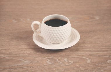 Ahşap masanın arkasında bir fincan kahve.