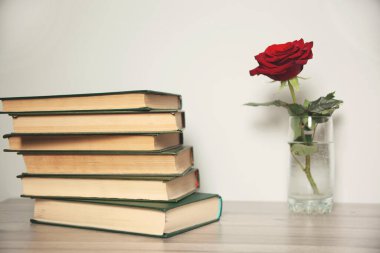 Kırmızı gül ve kitap masanın üstünde.