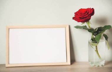 Masadaki kırmızı gül ve fotoğraf çerçevesi