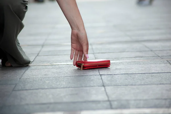 woman and a wallet on the ground in street