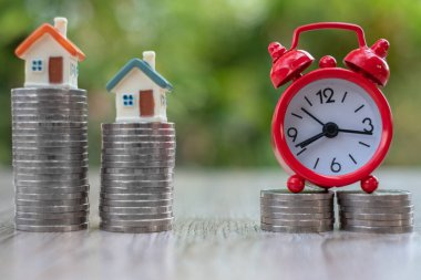 Mali ve bankacılık kavramları, gayrimenkul yatırımları ve finansal kavramlar için bozuk para yığınına ev ve kırmızı alarmlı saat. Bankanın mali birikimleri. İş büyümesi.