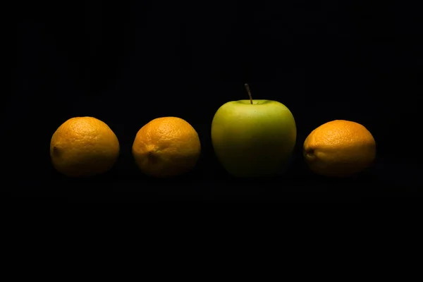 脱颖而出 成为不同的概念 黑暗背景下的柠檬中的苹果 — 图库照片