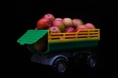 Oyuncak karavanında koyu arkaplanda olgun elma yığını