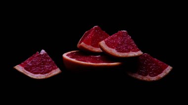 Koyu arkaplanda taze kırmızı greyfurt parçaları.