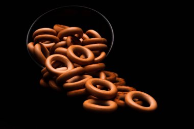 Koyu arkaplanda cam kasede ekmek simitleri.